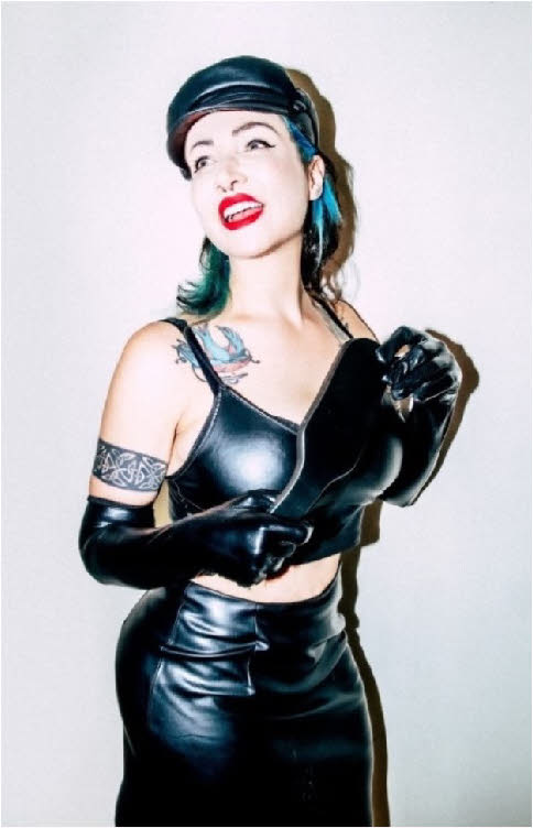 London domme in shiny leather outfit brandishing her spanking paddle